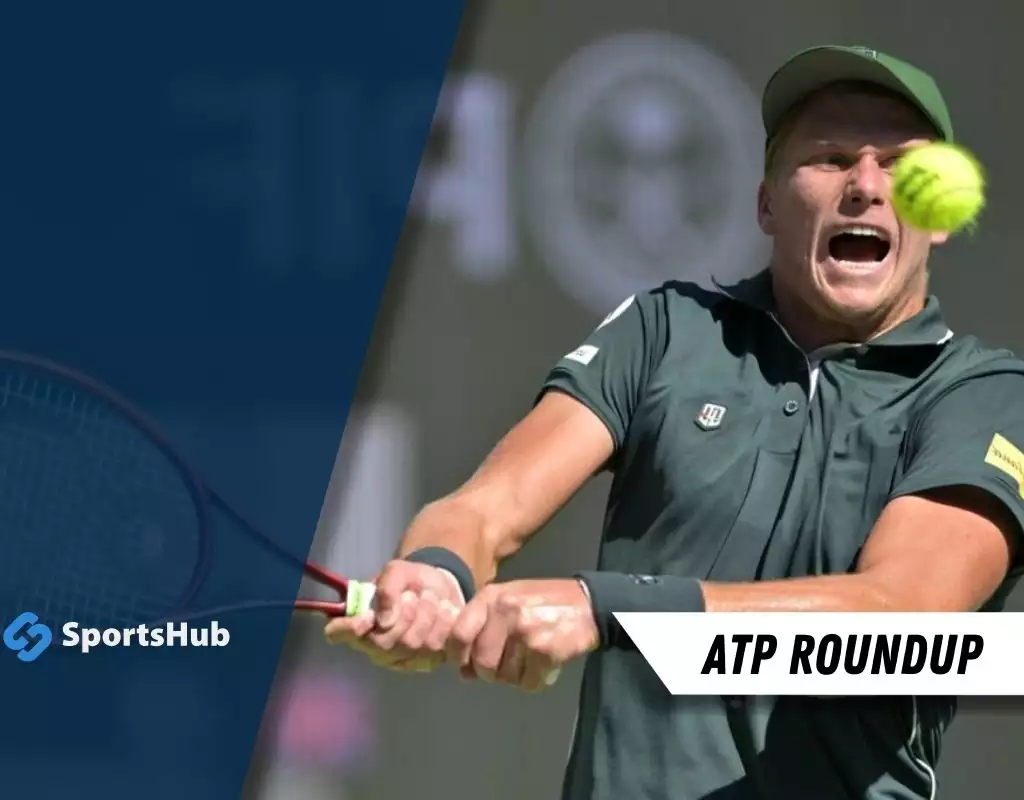 A tennis player in a dark polo shirt strikes a ball with a racket, set against a blurred background and showcasing sports action.