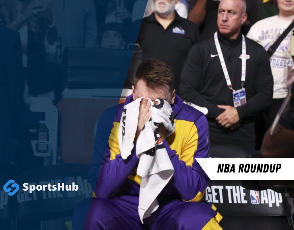 A player in a purple and gold uniform sits on the bench, towel in hand, with fans and team members in the background at an NBA game.