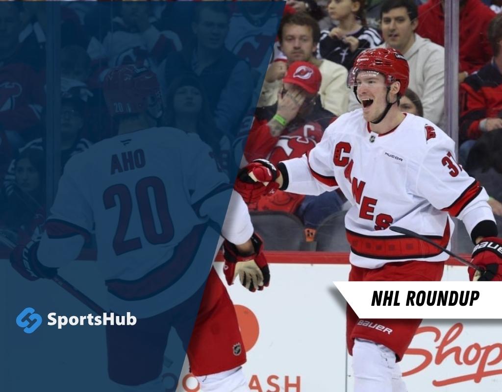 Carolina Hurricanes players celebrate a goal during a match, with fans in the background.
