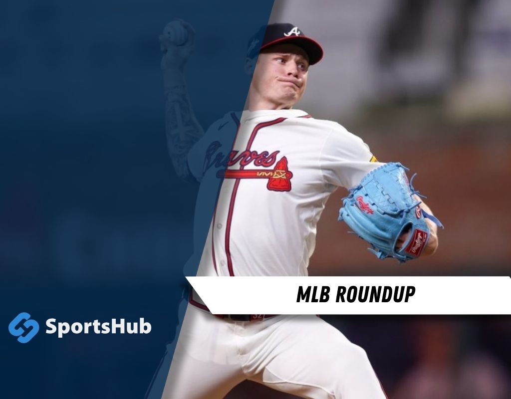 A baseball player in a white jersey and blue glove is poised to pitch