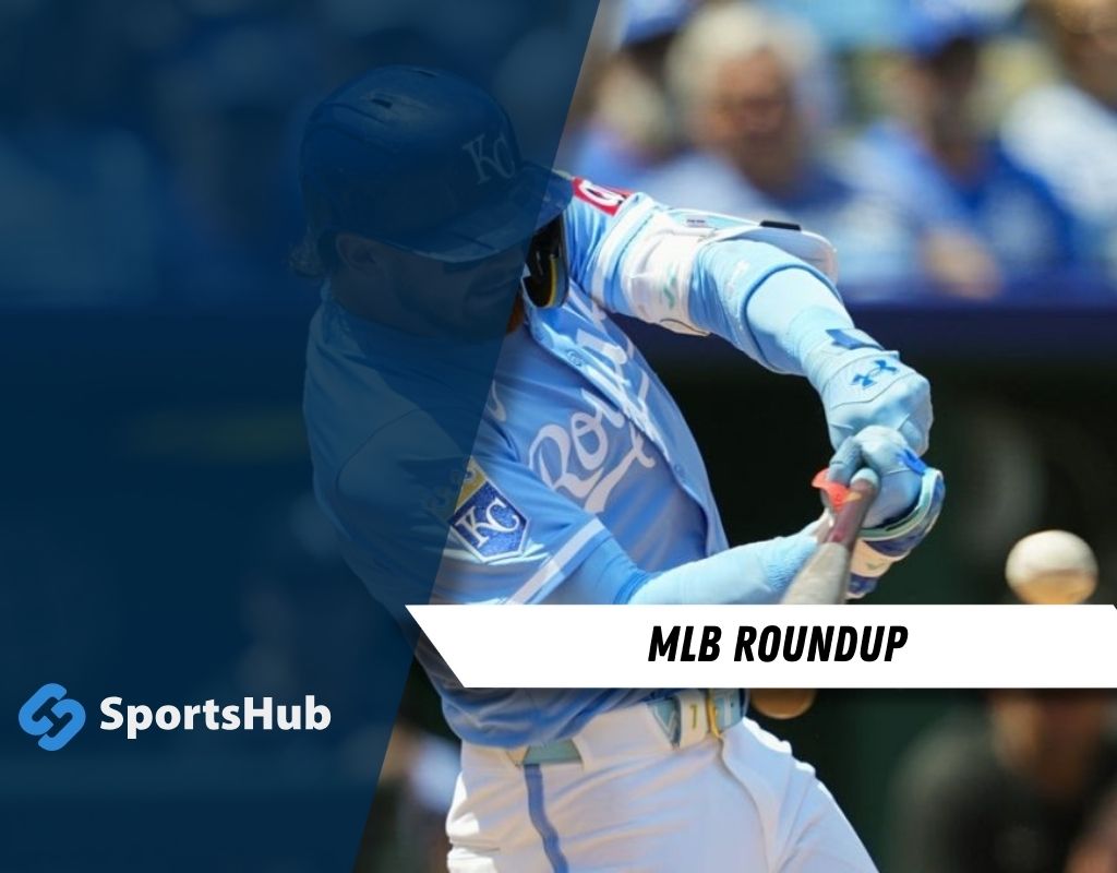 A player in a light blue baseball jersey swings a bat at a pitch, with fans and a stadium backdrop visible.