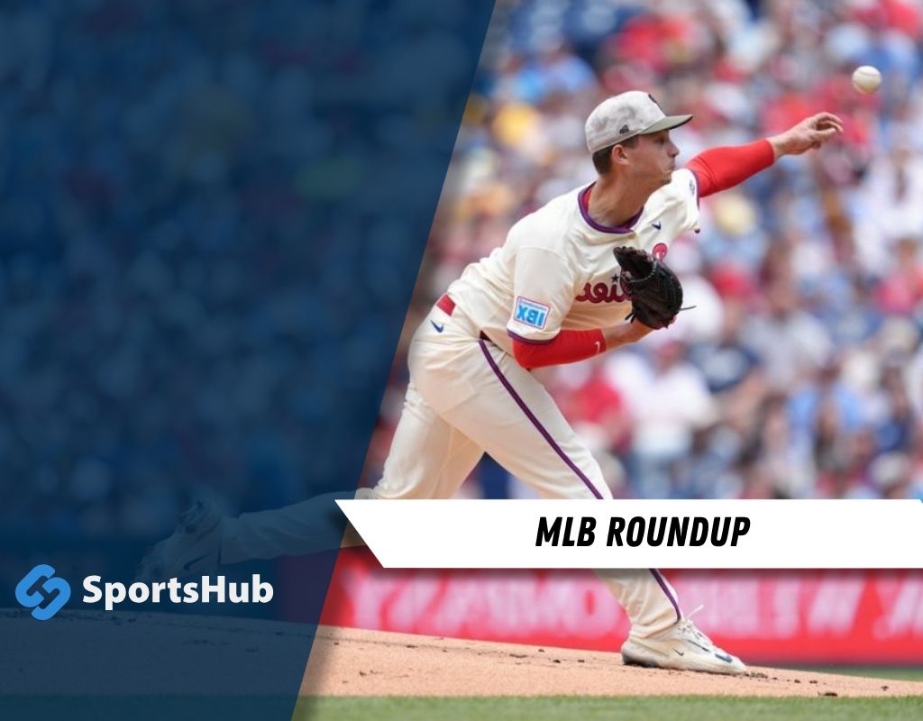 A baseball player in a white jersey prepares to pitch on a sunlit field, with fans visible in the blurred background.