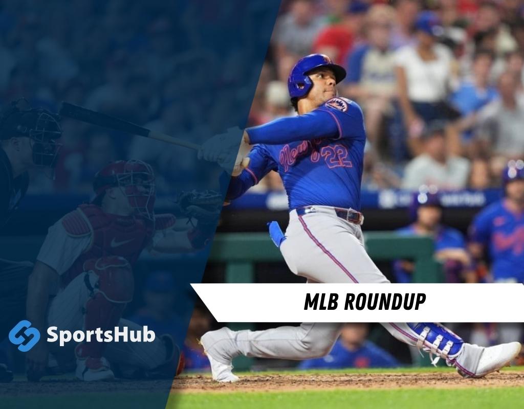 A baseball player swings a bat on the field, with stadium spectators and a scoreboard visible in the background.