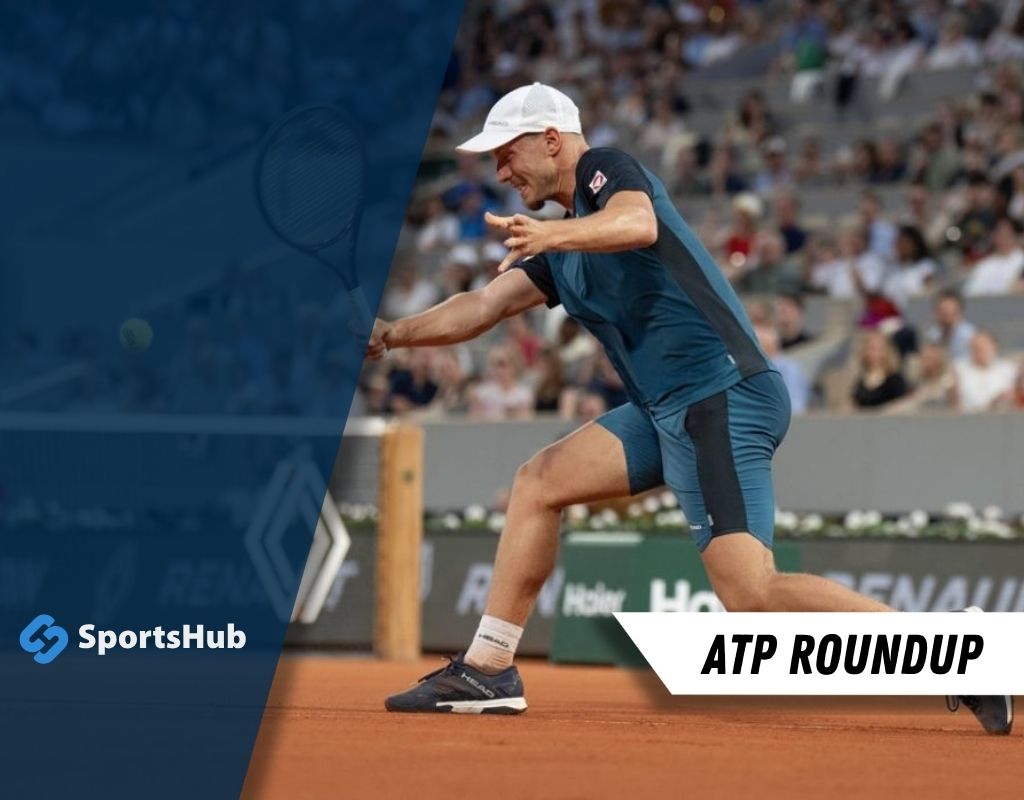 The image features a man dressed in a blue shirt and white hat, standing on a clay tennis court. In the background, there is a crowd watching the match.