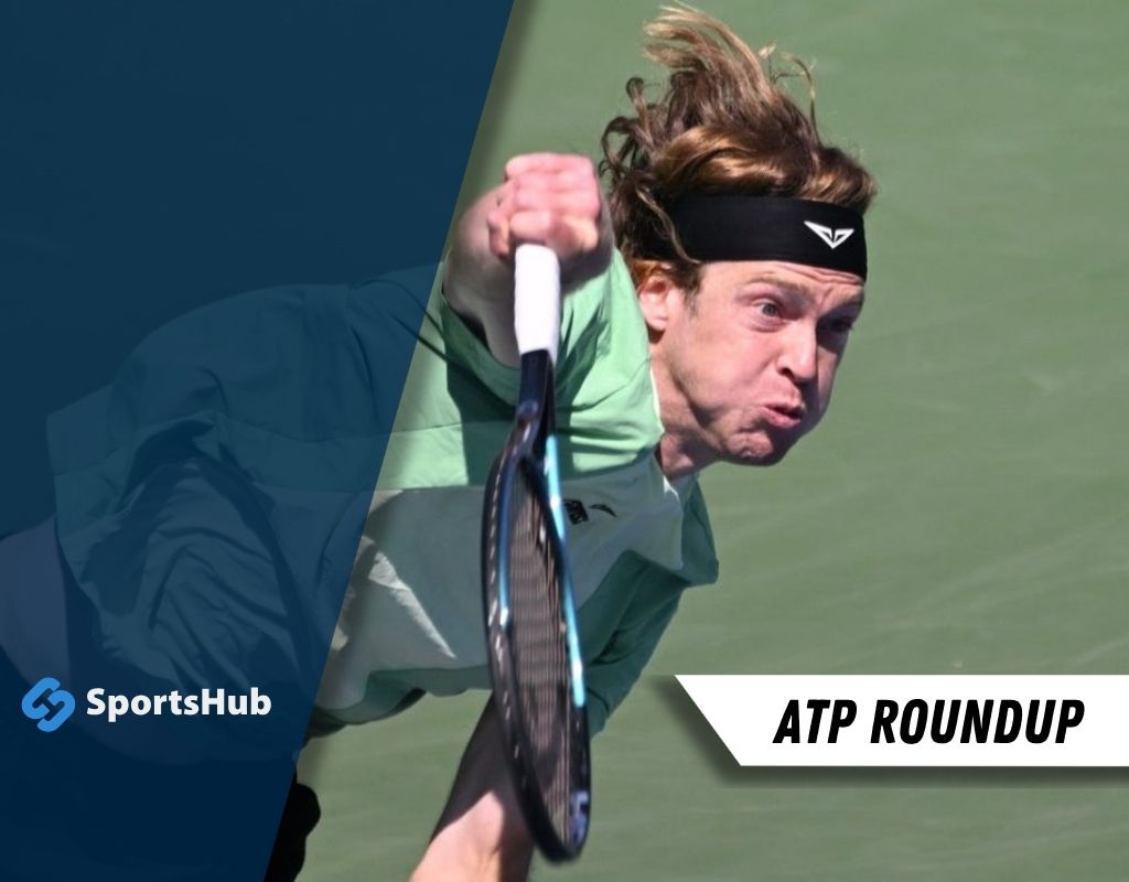 A tennis player in action, preparing to serve on a green court, wearing a green and white outfit.
